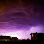 Valley with houses on it under a cloudy sky during storm in the night Valley with houses on it under a cloudy sky during storm in the night